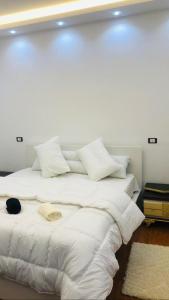 1 cama blanca grande con sábanas y almohadas blancas en شقه فندقيه ف ارقي مواقع بالزمالك en El Cairo