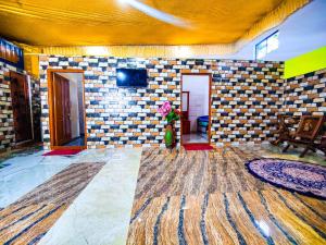 een woonkamer met een betegelde muur en een televisie bij Sahara Family Homestay in Mysore