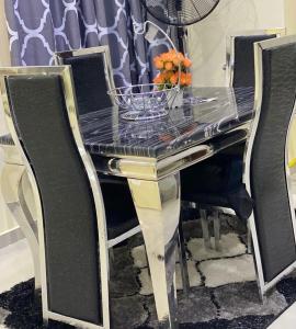 mesa de comedor negra y dorada con sillas y encimera de cristal en 3 Bedroom Spacious Apartment, en Okunola