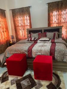 a bedroom with a large bed with two red ottomans at 3 Bedroom Spacious Apartment in Okunola
