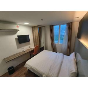 um quarto de hotel com uma cama, uma secretária e uma televisão em Sakura Elite Kuala Lumpur em Kuala Lumpur