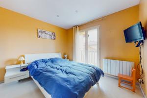 sypialnia z niebieskim łóżkiem i telewizorem w obiekcie Maison quartier résidentiel w mieście Saint-Priest