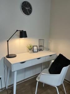 a desk with a lamp and a chair and a clock at Charming Homes - Studio 16 in Wolfsburg