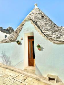 a white house with a roof with a door at Trulli Moon in Alberobello