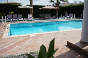 a swimming pool with chairs and umbrellas at Villa Coral Cove in Peyia