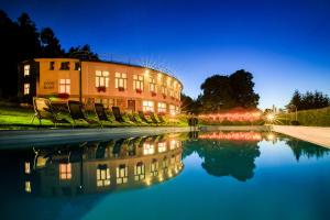 a building with chairs and a pool of water at night at Hotel Ermi in Jince