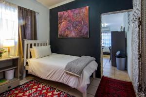 a bedroom with a bed and a painting on the wall at Yellow Door in Bloemfontein