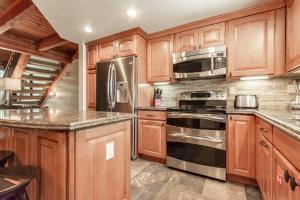 a kitchen with wooden cabinets and stainless steel appliances at Snowflower #47 - Updated 2 Bedroom & Loft, 3 Bath, Sleeps 8, Steps away from Free Town Shuttle in Mammoth Lakes