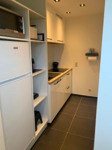 Q Guesthouse في Herzele: مطبخ فيه دواليب بيضاء وثلاجة بيضاء