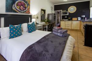a bedroom with a large white bed and a kitchen at Yellow Door in Bloemfontein