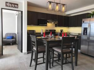 a kitchen with a table with chairs and a refrigerator at Sky Flat Panoramic View 2Brm@Avitat Link w/Pool &Gym in Antiguo Cuscatlán