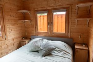 a bed in a wooden room with two windows at Logeren in Veere in Veere