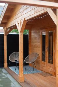 a wooden pergola with two chairs on a deck at Logeren in Veere in Veere