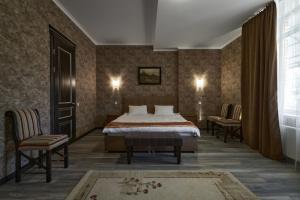 um quarto de hotel com uma cama e duas cadeiras em Podil City View em Kiev
