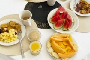 a table topped with plates of food with fruits and eggs at The Suite at Rhyne House book one or more bedroom in Montego Bay