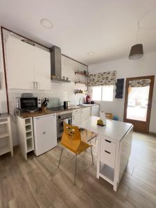 una cocina con armarios blancos y una mesa con una silla amarilla en SAN ISIDRO en Migueláñez