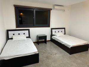 two beds in a room with a window at S Pool Villa Clark 天天别墅酒店 in Angeles