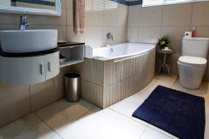 uma casa de banho com uma banheira, um lavatório e um WC. em Yellow Door em Bloemfontein