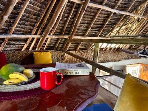 een tafel met een kopje koffie en een fruitschaal bij Kameleon Blue in Kizimkazi