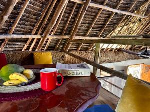 un tavolo con una tazza di caffè e un piatto di frutta di Kameleon Blue a Kizimkazi