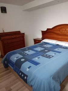 a bedroom with a bed with a blue comforter and a dresser at Apartamento Triana in Alovera