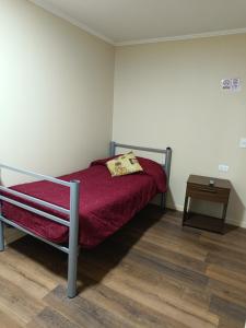 een slaapkamer met een bed met een rode deken en een tafel bij Hostal Ollague, habitaciones con baño privado in Calama
