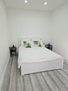a white bedroom with a white bed and wooden floors at Pad in Cardiff