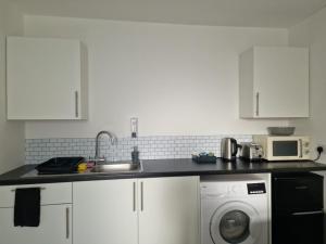 a kitchen with a sink and a washing machine at Pad in Cardiff