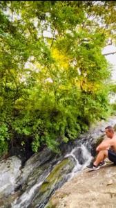 a man sitting on a bench next to a waterfall at Aconchego no Domo com Ofurô 7,5km centro Águas de Lindoia com CORTESIA in Águas de Lindóia