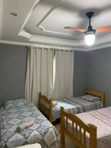 a bedroom with two beds and a ceiling fan at Casa confortável p/13/14/18 pessoas c 4/5/6 suítes in Belo Horizonte