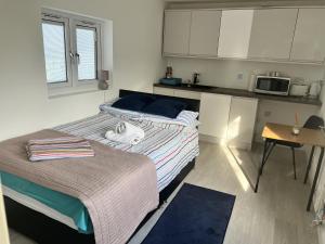 Duas camas num pequeno quarto com uma cozinha em Remarkable 1-Bed Outhouse Studio in Dagenham em Dagenham