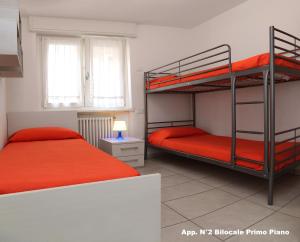 バルドリーノにある3V apartments Bardolinoのベッドルーム1室(赤いシーツを使用した二段ベッド2組付)