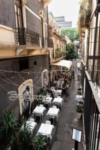 a patio with white tables and chairs on a street at Zefnea House in Catania