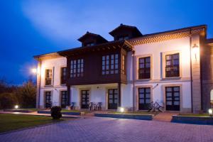 un gran edificio blanco con ventanas negras por la noche en La Casona de la Roza, en Valbucar