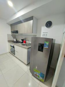 a kitchen with a refrigerator and a clock on the wall at Apartamento en Ibagué - parque deportivo in Ibagué