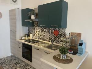 una cocina con armarios verdes y una encimera con fregadero en Loft panoramico Caltagirone centro en Caltagirone