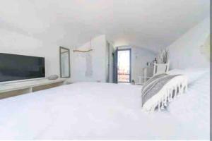 a white bedroom with a large bed and a flat screen tv at Jaccuzzi Romantic Suite in Firostefani,sea view! in Fira