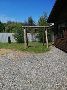 a swing set in a yard next to a house at Cabaña Dos Ríos in Villarrica