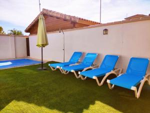 un grupo de sillas azules y un paraguas en un patio en Casa Rural La Dehesa de Toledo a 5 minutos de Puy du Fou España, en Cobisa