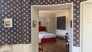 1 dormitorio con 1 cama y pared cubierta de papel pintado en Chambres d'Hôtes Manoir de Beaumarchais en Les Chapelles-Bourbon