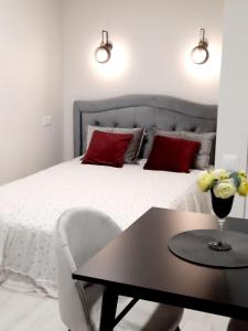 Schlafzimmer mit einem Bett mit einem Tisch und roten Kissen in der Unterkunft P Komunos Apartamentai Netoli Akropolio in Klaipėda
