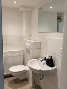Baño blanco con aseo y lavamanos en Ihr Zimmer in Freital bei Dresden en Freital