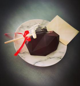 una torta al cioccolato su un piatto con un nastro rosso di Nid’Ange a Piolenc