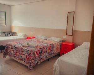 1 dormitorio con 2 camas y mesa roja en Pousada Costa da Riviera, en Bertioga