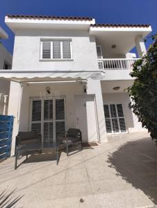 Biały dom z dwoma krzesłami przed nim w obiekcie Kato Paphos 2 Bedroom House - Tourist location w Pafos