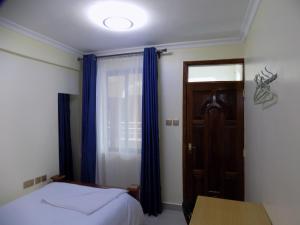 Schlafzimmer mit einem Bett und einem Fenster mit blauen Vorhängen in der Unterkunft LANACA RESORT in Litein