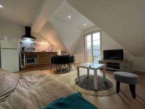 a living room with a table and a kitchen at Villa La Butte, Appartements Chaleureux au Cœur de La Bourboule in La Bourboule