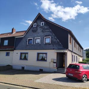 ein Haus mit einem roten Auto, das davor geparkt ist in der Unterkunft Gästehaus Familie Rinke in Bad Harzburg