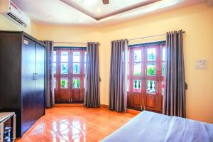 a bedroom with a bed and two large windows at 'Golden Sunset' 3bhk beach villa in Benaulim