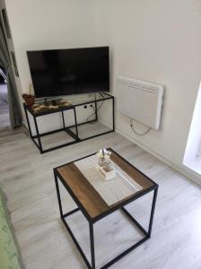 ein Wohnzimmer mit 2 Tischen und einem Flachbild-TV in der Unterkunft L'escale CDG Astérix Park d'exposition in Louvres
